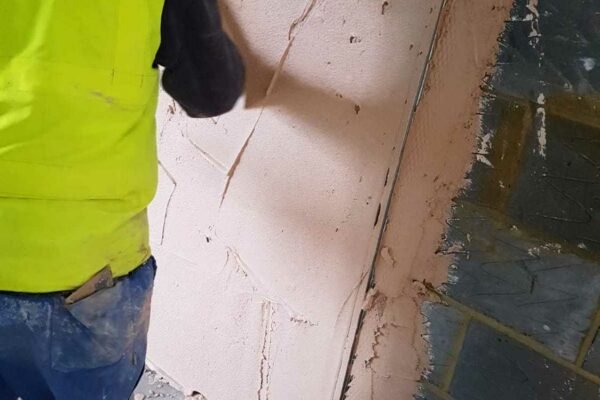 Man in hi-vis doing exterior pink plastering