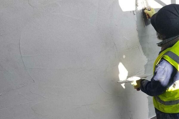 Man in hi-vis doing exterior wall rendering