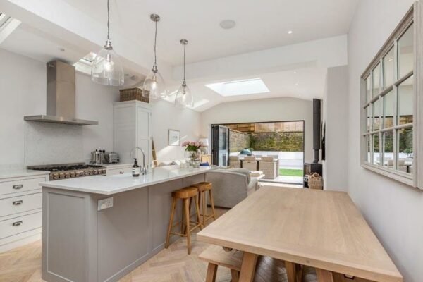 Modern clean white and grey interior of a kitchen with large doors to garden