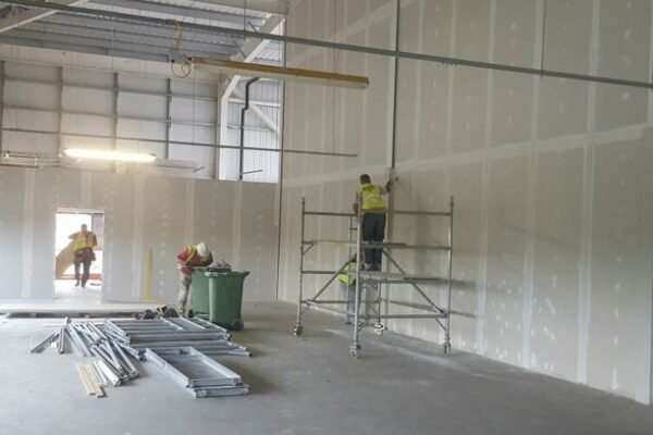 Men in hi-vis plastering interior walls