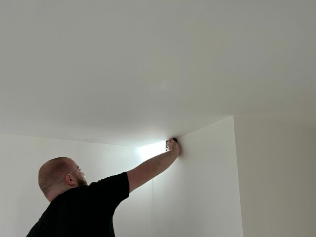 Man doing quality checks on a ceiling with a leveller