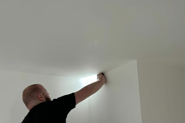 Man doing quality checks on a ceiling with a leveller