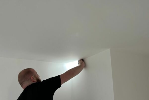 Man doing quality checks on a ceiling with a leveller